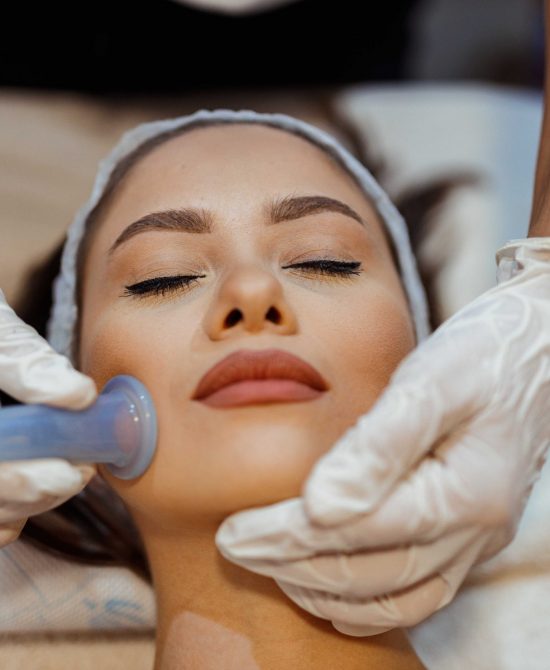 Beautiful young woman lying down in the beauty clinic and having a facial cupping massage treatment to stimulate blood circulation